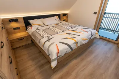 a bedroom with a large bed and a wooden floor at Vila Klif vacation home with sauna and terrace in Cerklje na Gorenjskem