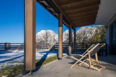 a bench on a porch with mountains in the background at Vila Klif vacation home with sauna and terrace in Cerklje na Gorenjskem