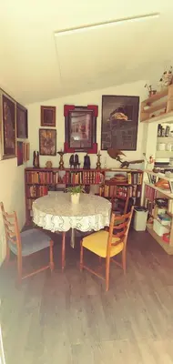 a dining room with a table and chairs and books at Dom AteLJe in Ljubljana