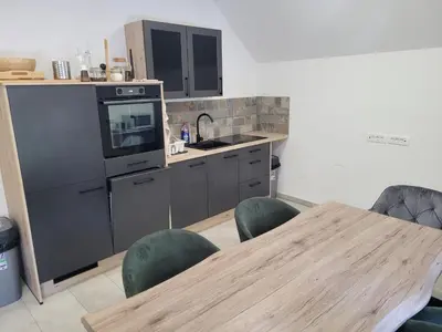 a kitchen with a wooden table and chairs and a table and a counter at Kranj Leisure Apartment in Kranj