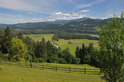 a pasture with a fence and mountains in the background at Apartments MM in Muta