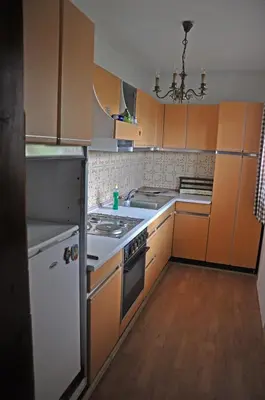a kitchen with orange cabinets and a white stove top oven at Apartments MM in Muta