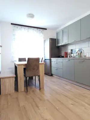 a kitchen with a wooden table and a dining room at Apartma Vodrice in Slappe dʼIdria