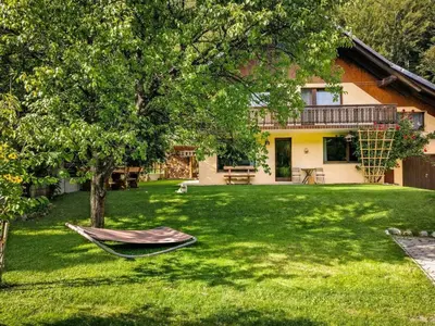 a yard with a hammock in front of a house at Cozy 3BR Alpine House in Gozd Martuljek