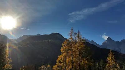 a view of a mountain with the sun in the sky at Cozy 3BR Alpine House in Gozd Martuljek