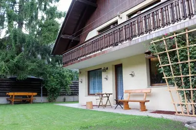 a patio with two picnic tables and a balcony at Cozy 3BR Alpine House in Gozd Martuljek