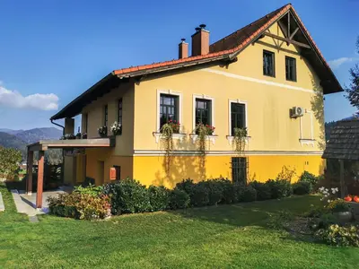 a yellow house with flower boxes on the windows at Geratičevo in Lovrenc na Pohorju
