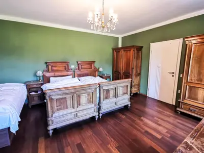 a bedroom with a large bed and a chandelier at Geratičevo in Lovrenc na Pohorju