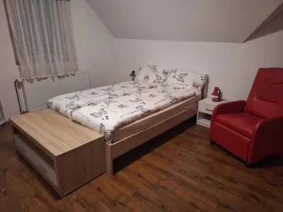 a bedroom with a bed and a red chair at Apartma Studio Bogi in Kranjska Gora