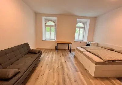 a bedroom with a bed and a couch and two windows at Apartment Bon Voyage II in Maribor