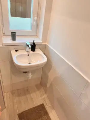 a white bathroom with a sink and a window at Apartment Bon Voyage II in Maribor