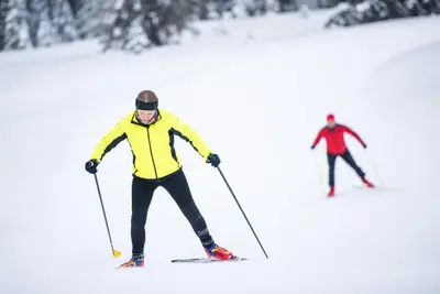 two people skiing down a snow covered slope at Hotel Natura in Zreče