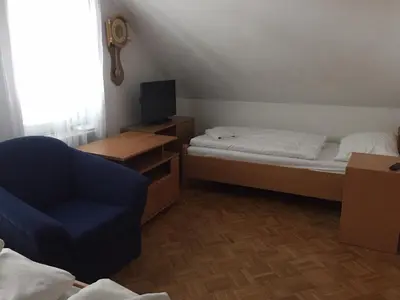a small room with two beds and a blue chair at Apartmaji Kranjska Gora in Kranjska Gora