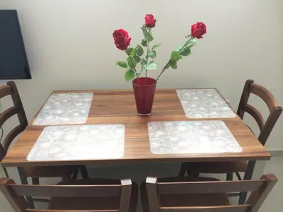 a wooden table with a vase with red roses on it at Apartmaji Kranjska Gora in Kranjska Gora