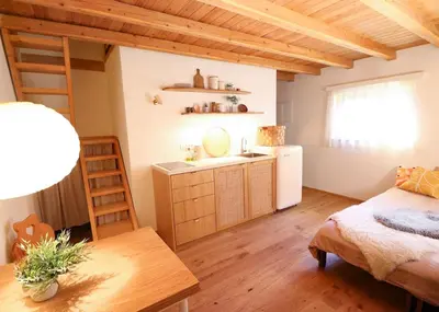 a bedroom with a bed and a kitchen with a sink at Designer Riverfront Cottage in Podljubelj