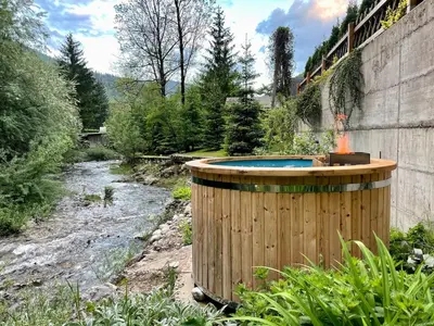 a hot tub in a garden next to a river at Designer Riverfront Cottage in Podljubelj