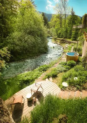 a wooden deck with two chairs next to a river at Designer Riverfront Cottage in Podljubelj