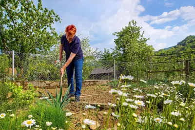 a woman is gardening in a garden at Farm Stay Pirc - Hayloft Apartment in Laško