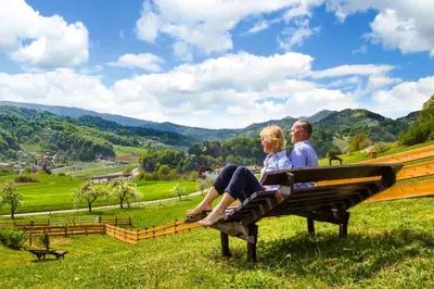 a man and woman sitting on a bench in a field at Farm Stay Pirc - Hayloft Apartment in Laško