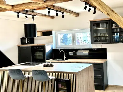 a kitchen with black cabinets and a kitchen island with chairs at City Central Loft with Parking in Maribor