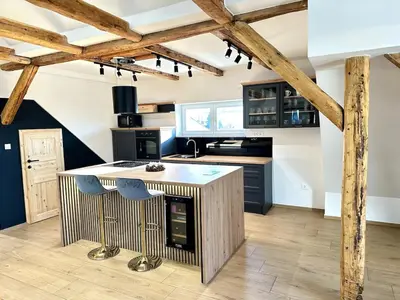 a kitchen with a large island in a room with wooden beams at City Central Loft with Parking in Maribor