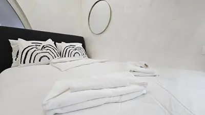 a white bed with white towels and a mirror at Teeny tiny in Šentvid