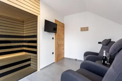 a living room with two blue chairs and a tv at Hiša Urma in Celje