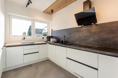 a kitchen with white cabinets and a large window at Hiša Urma in Celje