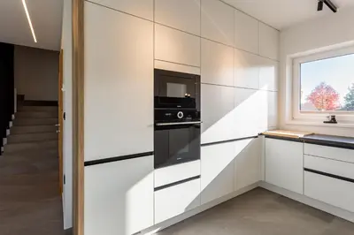 a kitchen with white cabinets and a window at Hiša Urma in Celje