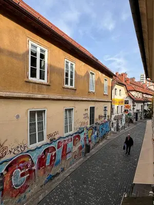 a man walking down a street next to buildings with graffiti at Staro mesto & Dragon bridge in Ljubljana