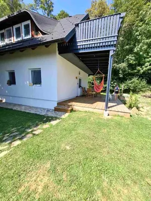 a house with a porch with a hammock at Apartma Pohorc - Macesen in Pohorje