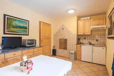 a kitchen with wooden cabinets and a white table at Authentic Pohorje house with riverside outdoor sauna in Oplotnica