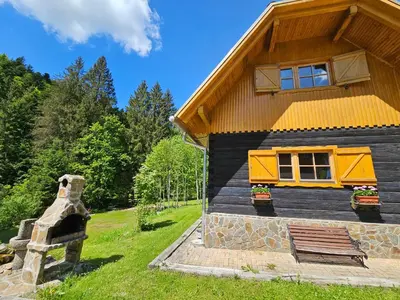 a log cabin with a yellow roof and a window at Authentic Pohorje house with riverside outdoor sauna in Oplotnica