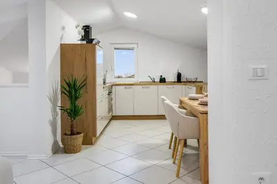 a kitchen with white cabinets and a table with a potted plant at Apartment Mandi By DIMBIKES in Ajdovščina