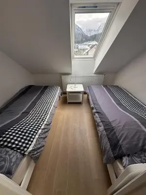 two beds in a small room with a window at GOLOB Apartment Kranjska Gora in Kranjska Gora