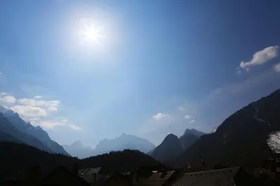 a view of a mountain valley with the sun in the sky at GOLOB Apartment Kranjska Gora in Kranjska Gora