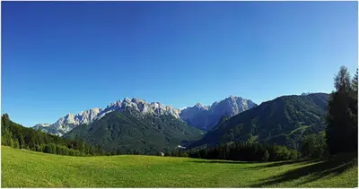 a green field with mountains in the background at GOLOB Apartment Kranjska Gora in Kranjska Gora