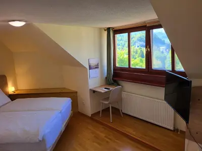 a bedroom with a bed and a desk and a television at Apartment Alpine Lake in Bled