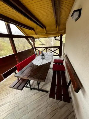 a porch with a wooden table and two red chairs at Apartma Zidanca Bele in Dolenjske Toplice