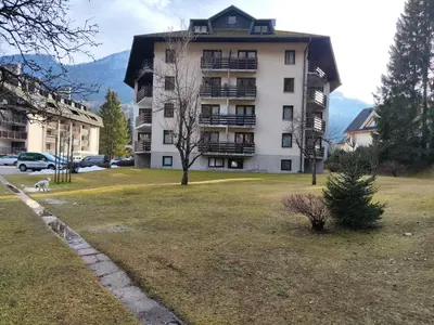 a large apartment building with a dog in a yard at Planica Studio in Kranjska Gora in Kranjska Gora