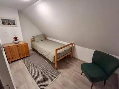 a small bedroom with a bed and a chair at Apartma Hiška Vrh in Stari Trg pri Ložu