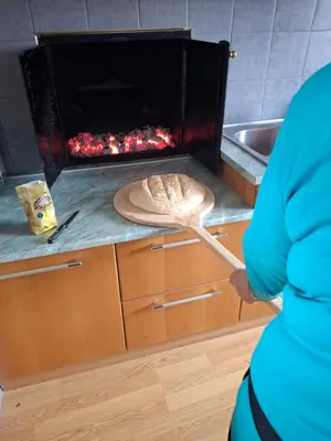 a person standing in a kitchen with a oven at Apartma Hiška Vrh in Stari Trg pri Ložu