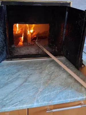 a fire oven with two wooden sticks in it at Apartma Hiška Vrh in Stari Trg pri Ložu