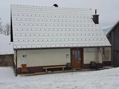 a small building with a bench in the snow at Apartma Hiška Vrh in Stari Trg pri Ložu