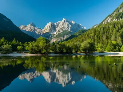 a mountain reflection in a lake with trees and mountains at Apartment Pr' Kavač by Interhome in Rateče