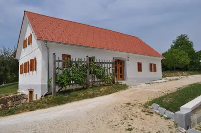a white house with a red roof and a dirt road at Apartments Koptur in Škocjan