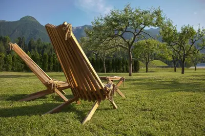 a wooden rocking chair sitting in a field of grass at Green Garden Apartments Soklič in Bohinj
