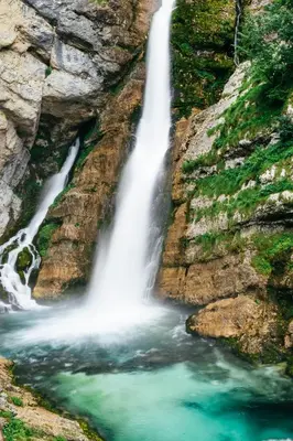 a waterfall on the side of a rocky cliff at Green Garden Apartments Soklič in Bohinj