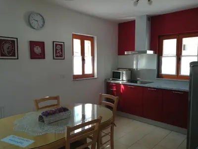 a kitchen with a dining table and a kitchen with red cabinets at Hiša Kranjc in Kobarid