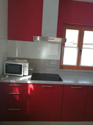 a kitchen with red cabinets and a microwave at Hiša Kranjc in Kobarid
